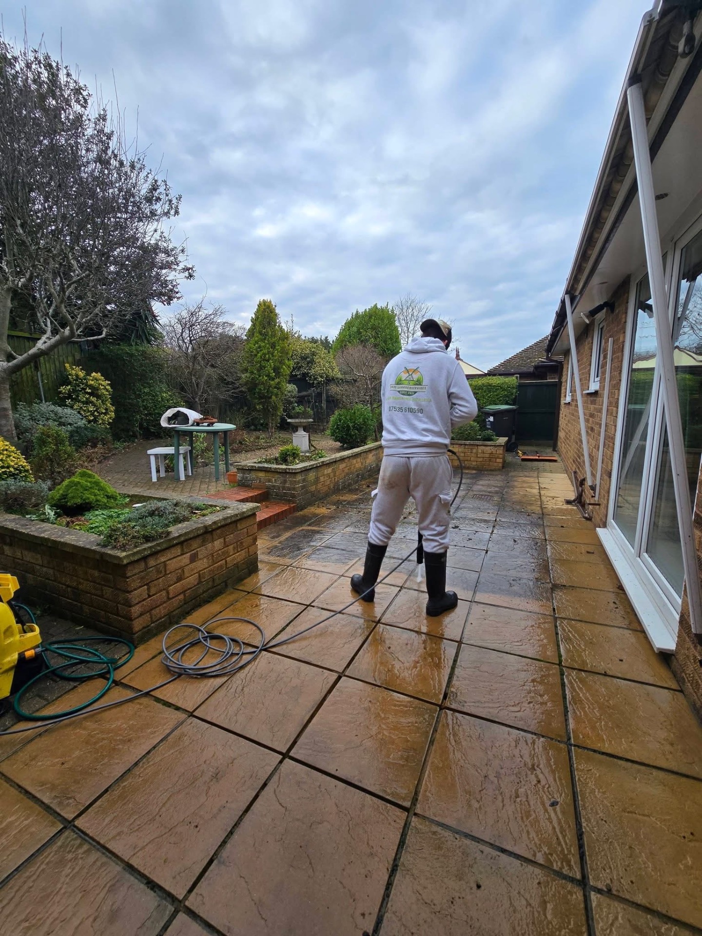 Pressure washing a rear patio to restore the paving